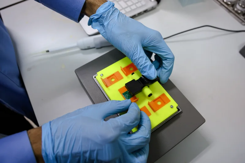 Laboratory technician operating eProfiler sensor device with gloved hands